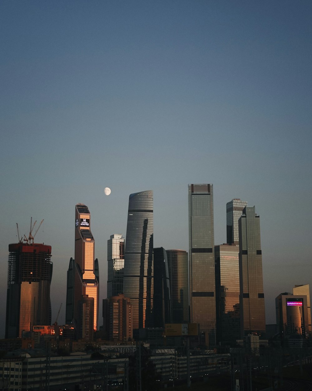 a city skyline with skyscrapers and a full moon in the sky