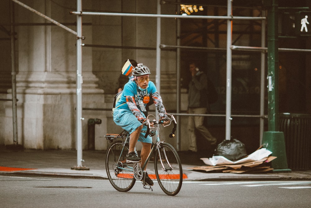 a man riding a bike down a street next to a tall building