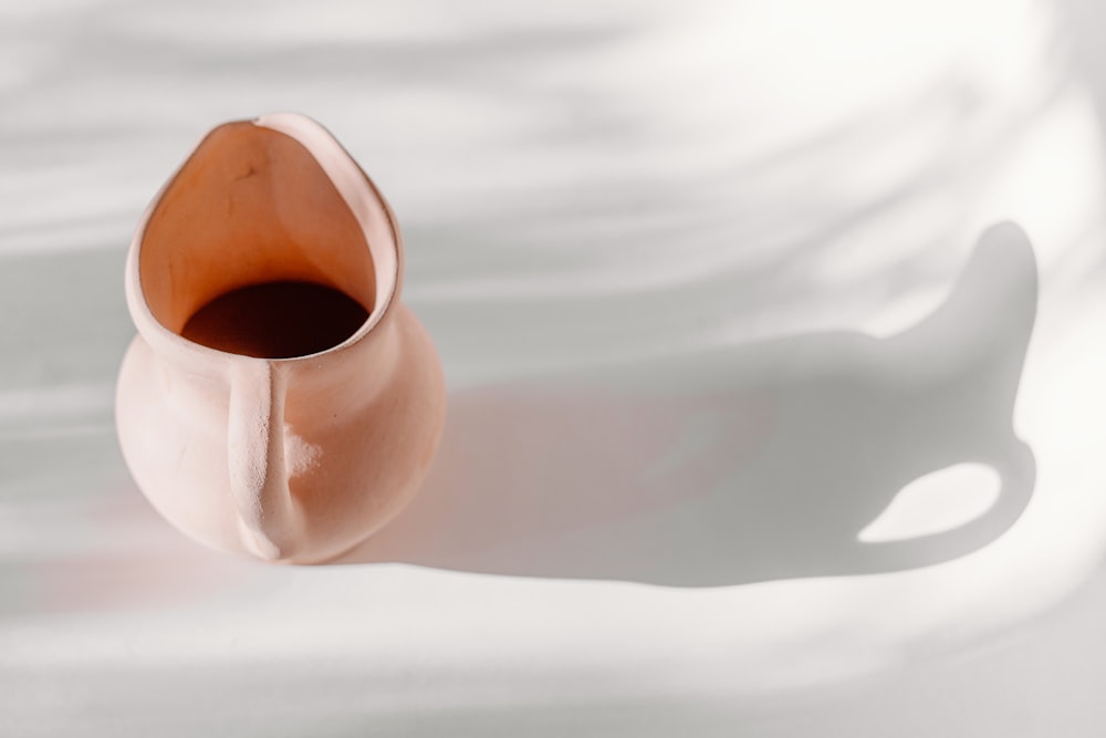 a brown vase sitting on top of a white table