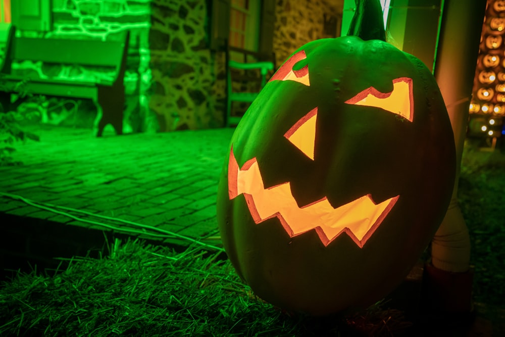 a carved pumpkin sitting on top of a lush green field