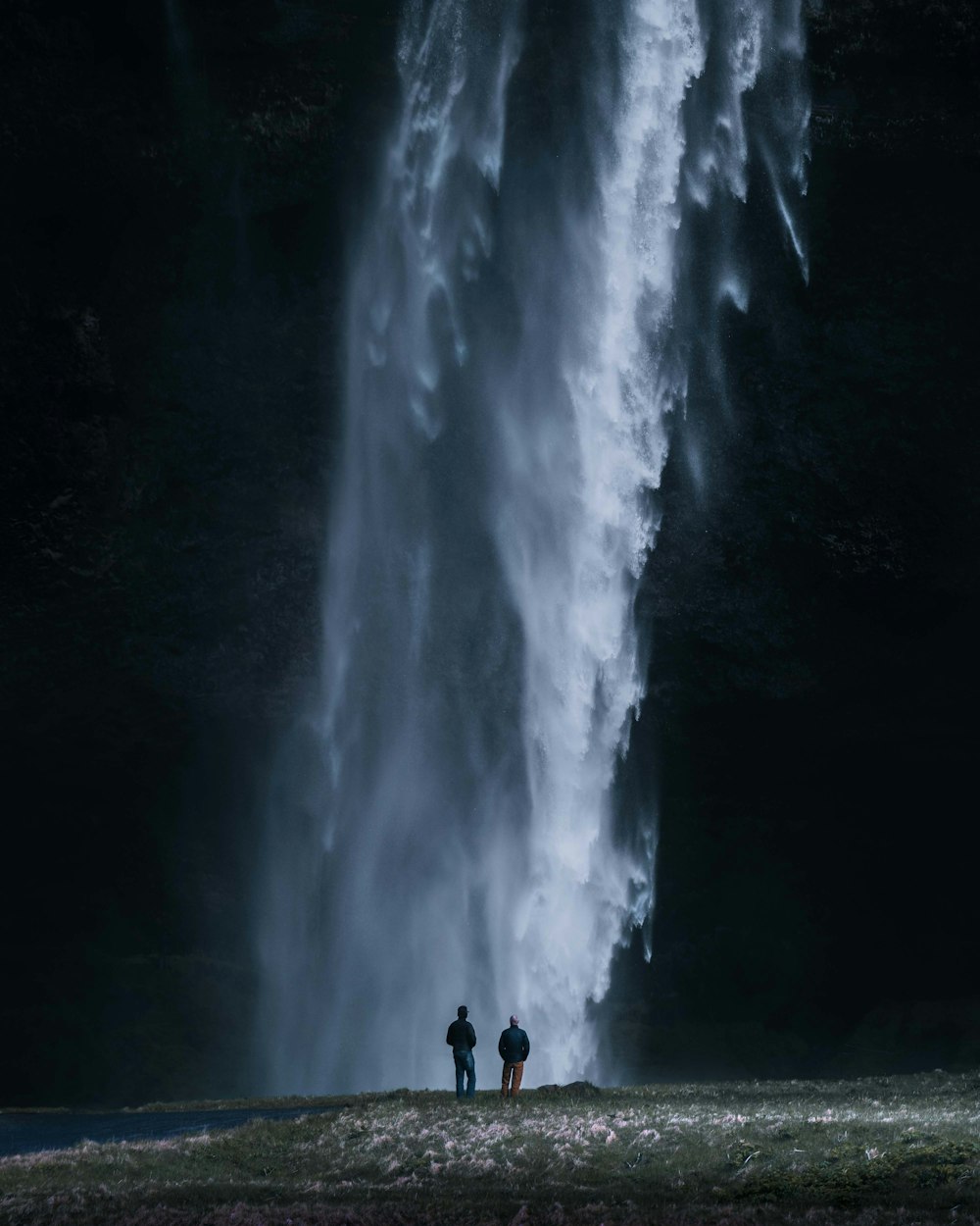 two people standing in front of a large waterfall