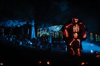An outdoor haunted scene with skeletons and eerie lights.