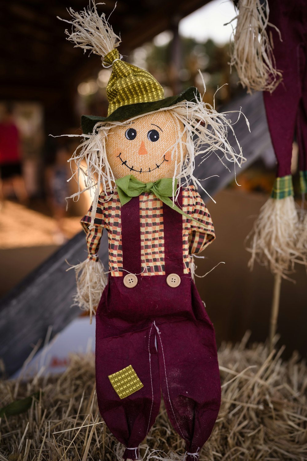 a scarecrow with a hat and overalls standing in hay