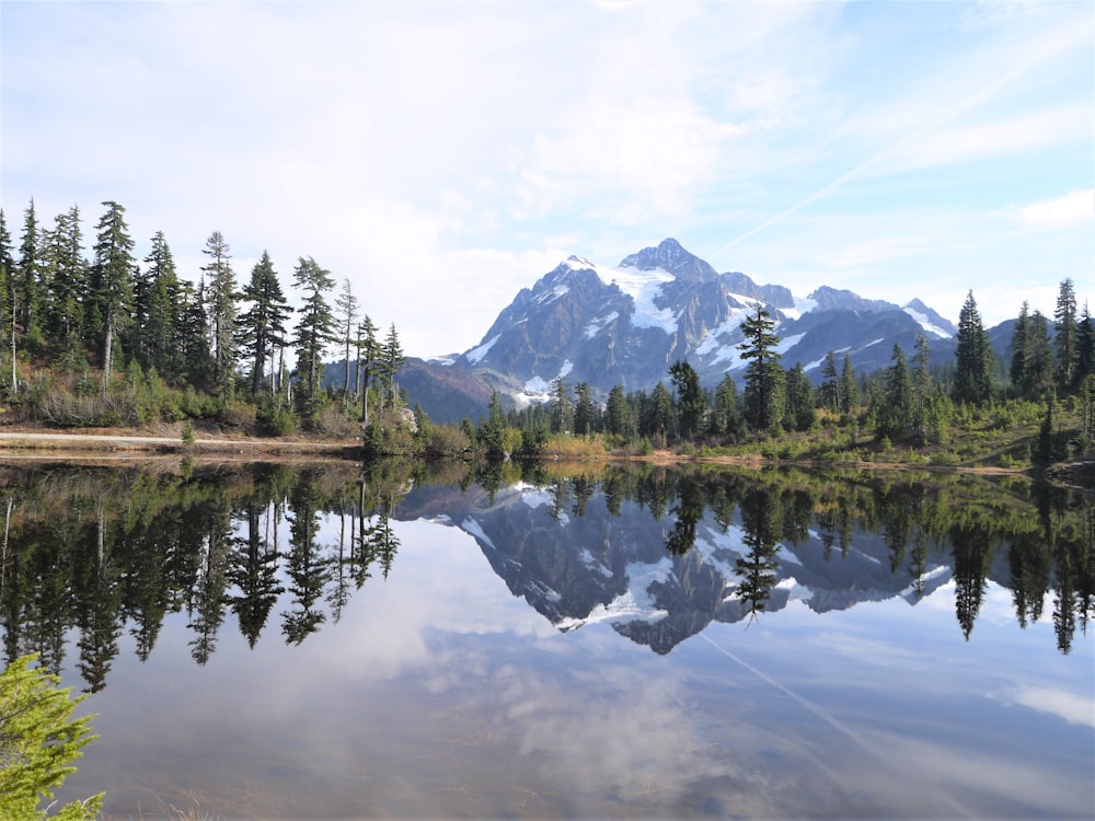 a mountain range is reflected in the still water of a lake