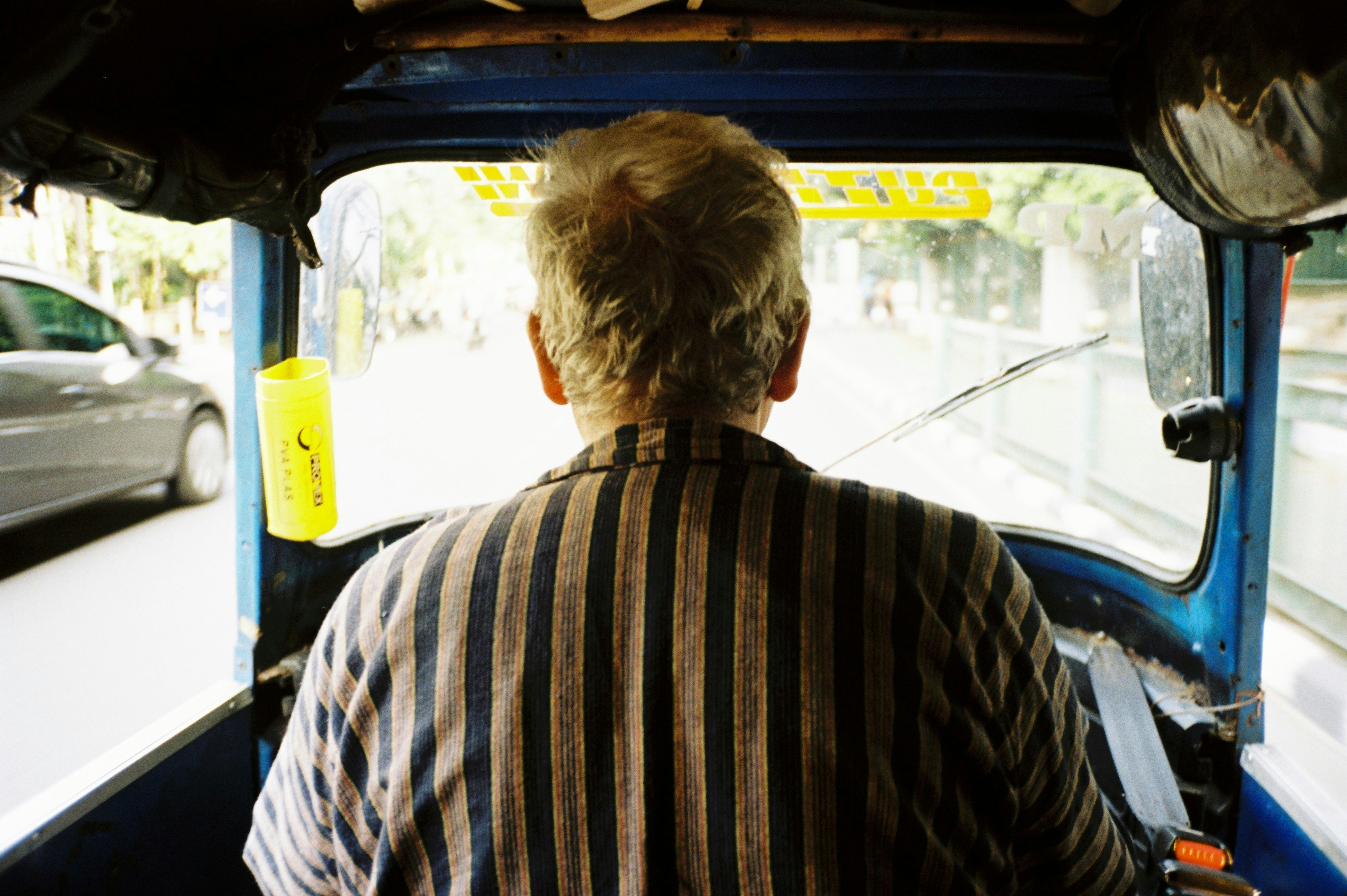 a man driving a blue truck down a street