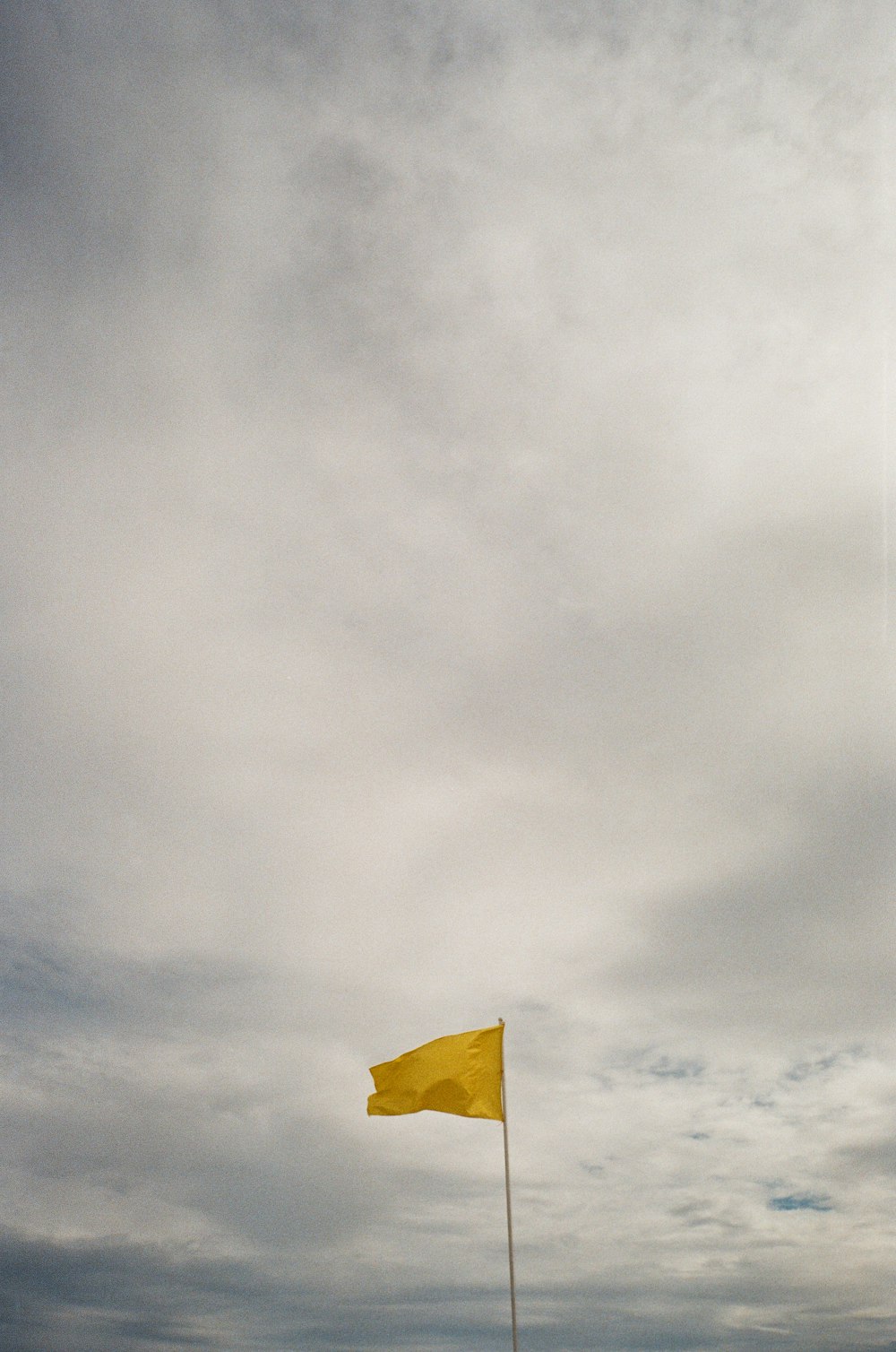 a yellow flag flying in a cloudy sky