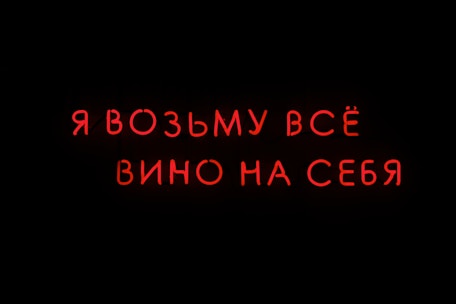Bright red neon text in Russian on a black background.