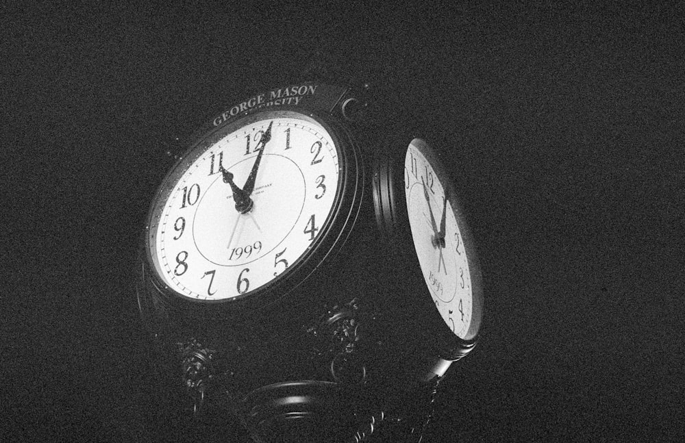 a black and white photo of two clocks