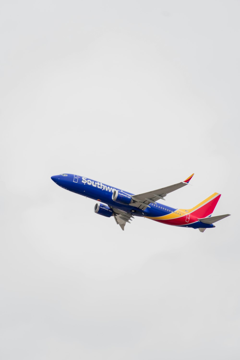 a blue and red airplane flying in the sky