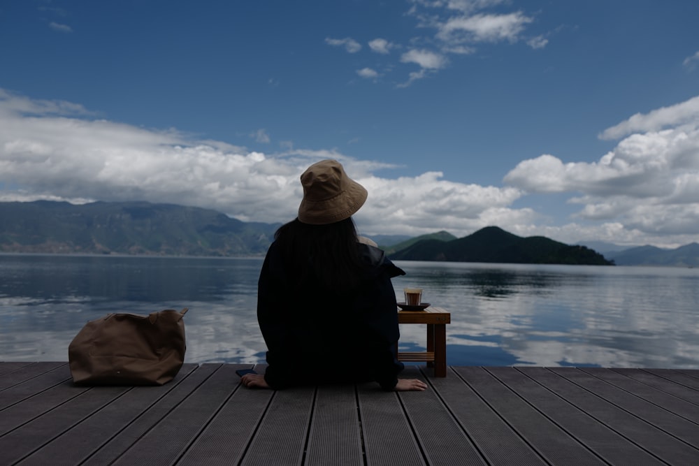 a person sitting on a dock looking at the water