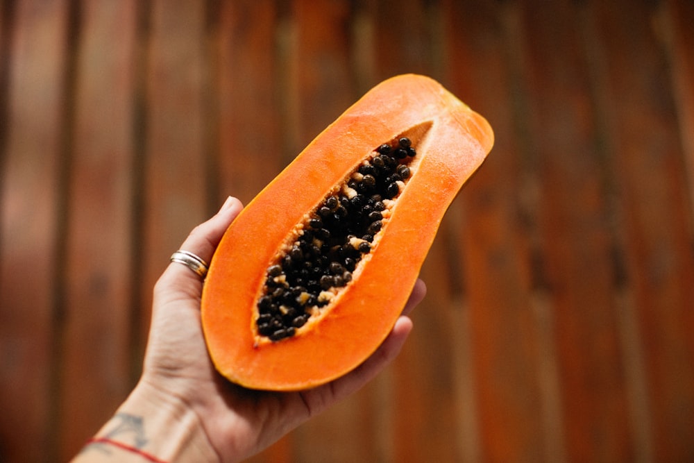 a person holding a half of a papaya