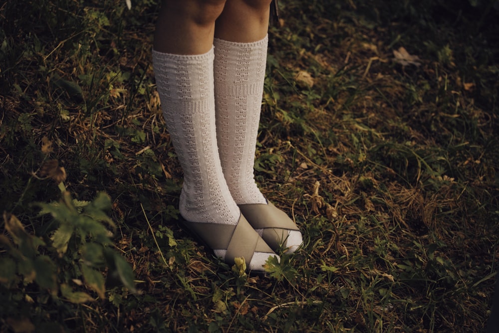 a woman in white socks and socks standing in the grass