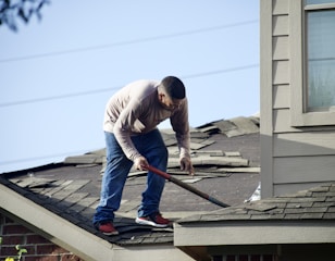 a man with a hammer on top of a roof