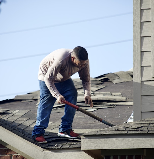 a man with a hammer on top of a roof