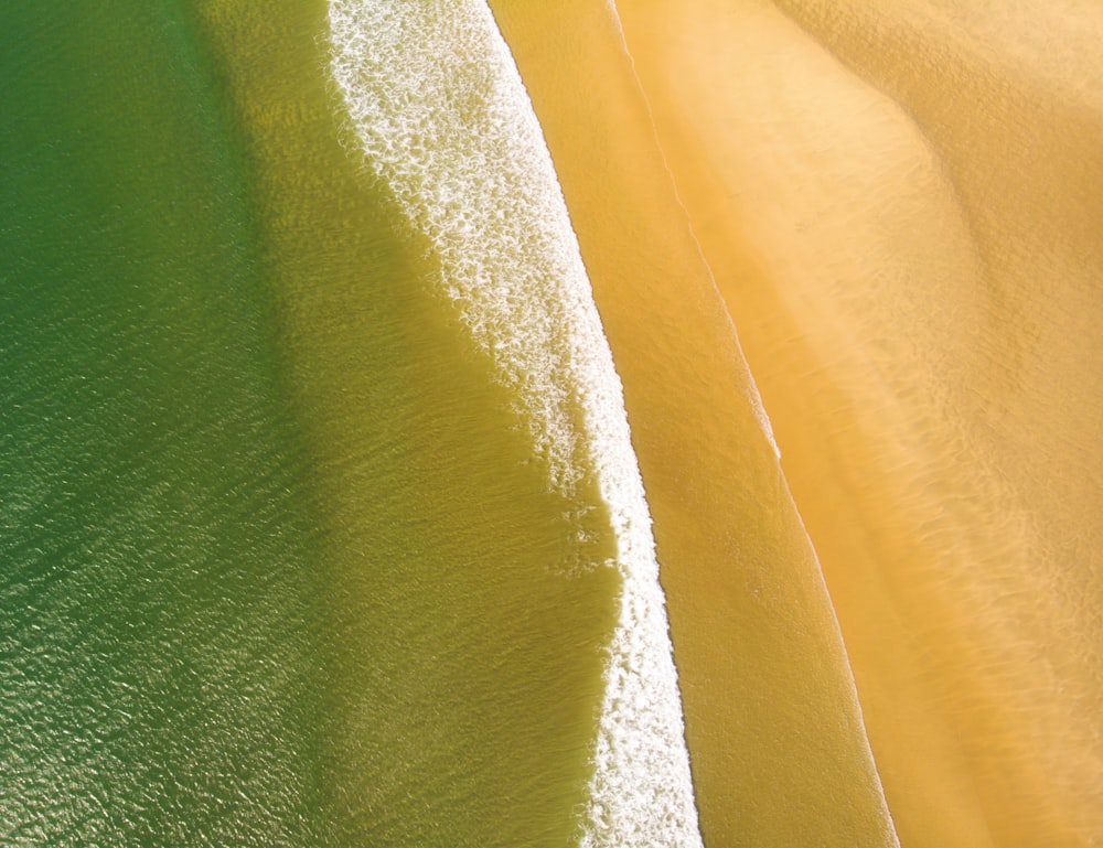 an aerial view of a sandy beach with waves