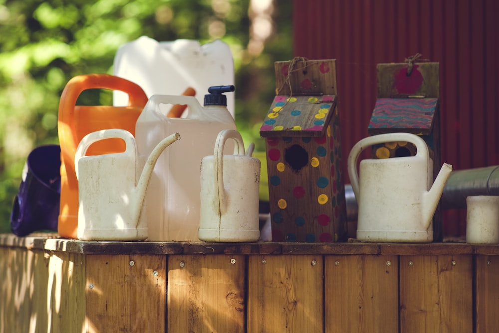 a wooden table topped with lots of white jugs and containers