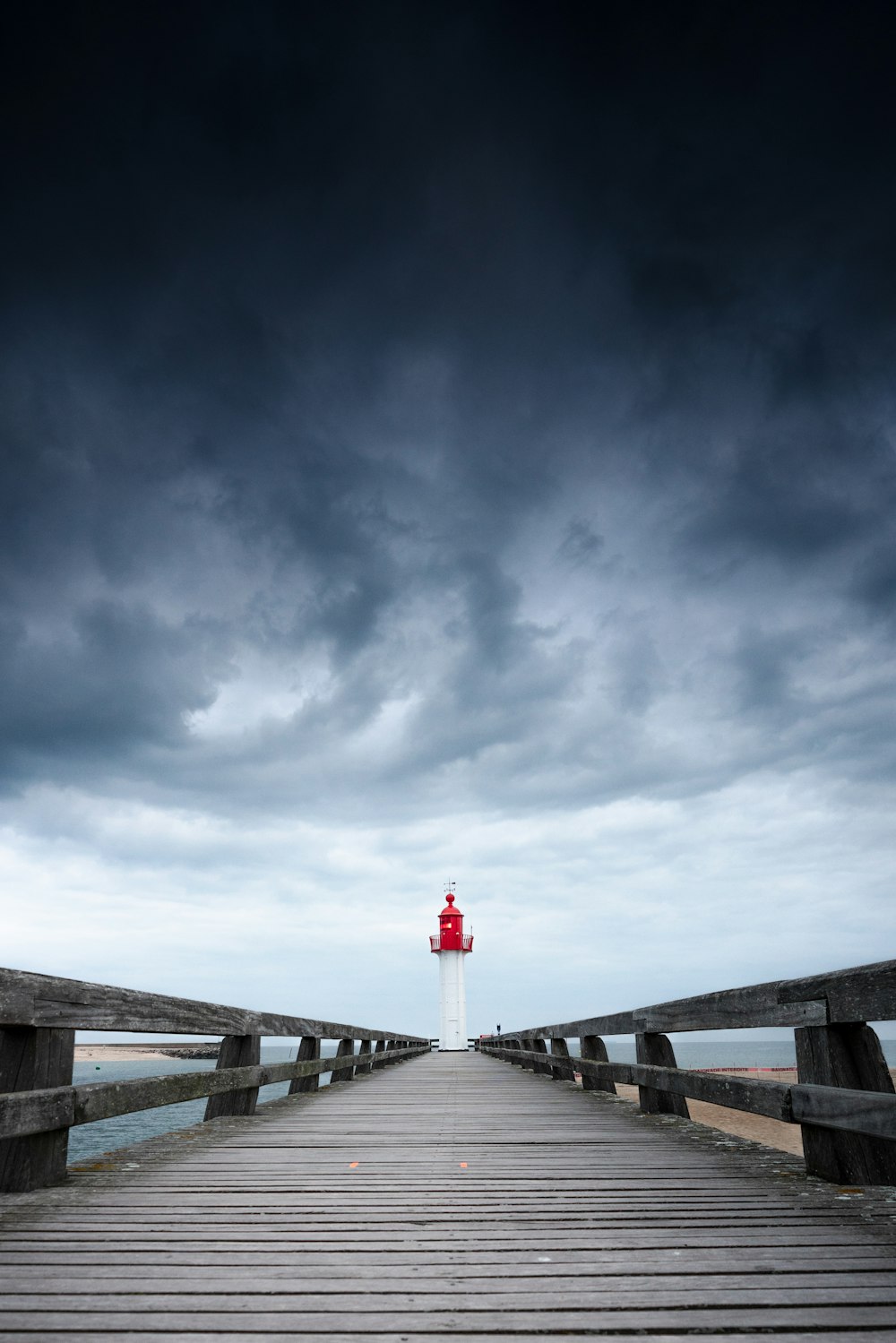 a wooden pier with a light house in the distance