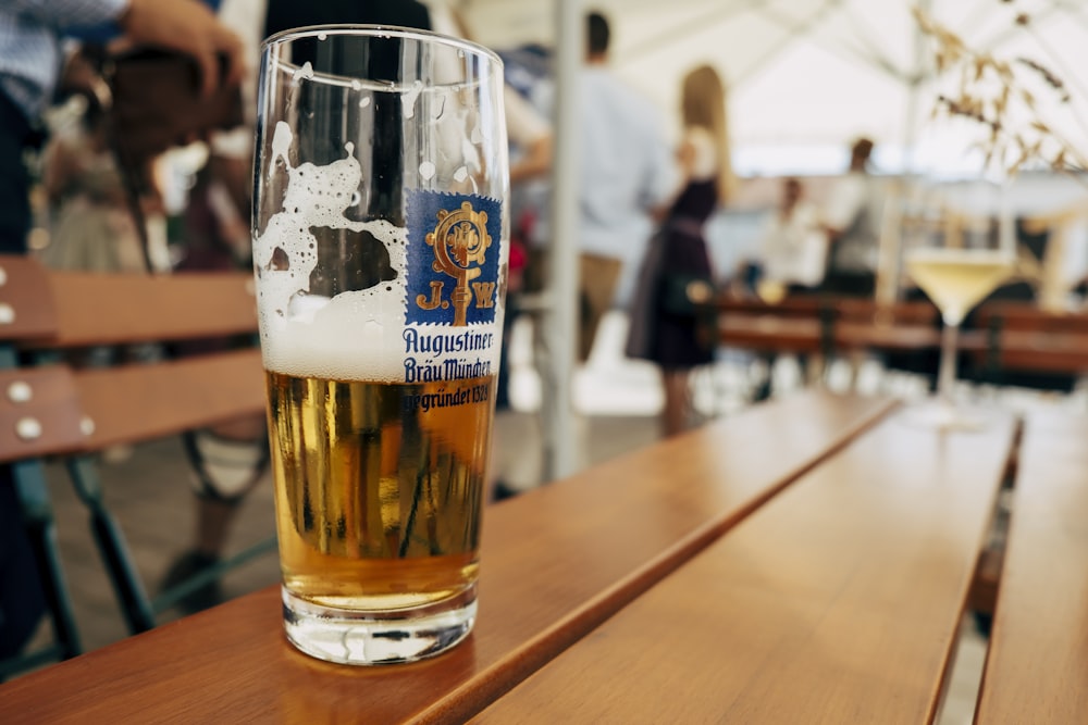 a glass of beer sitting on top of a wooden table