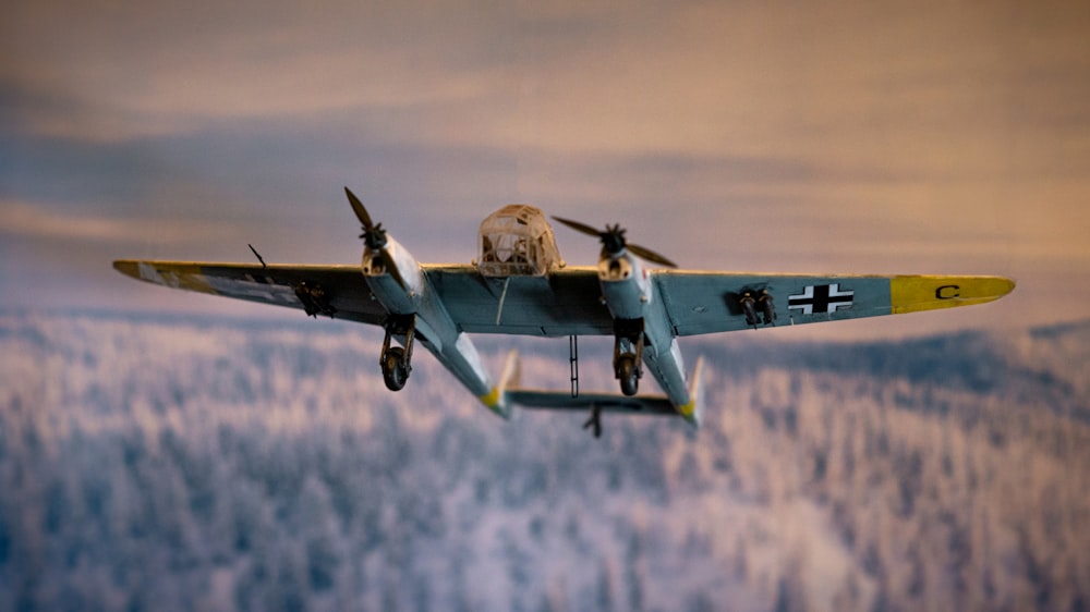 a small airplane flying through the air with trees in the background