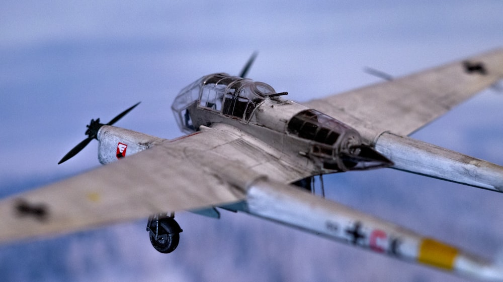 a model airplane flying in the sky with mountains in the background