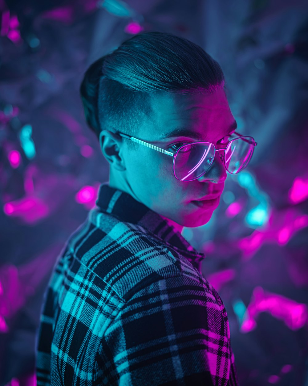 a man wearing glasses standing in front of a purple and blue background