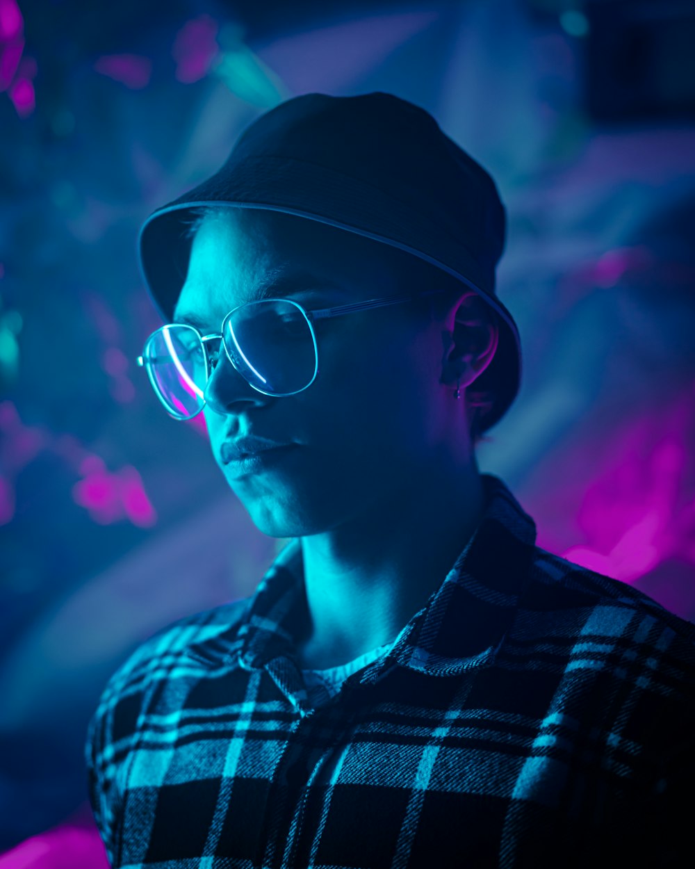 a man wearing glasses and a hat in a dark room