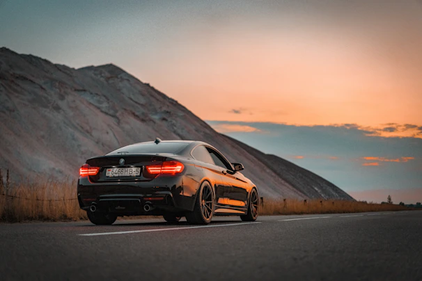 A sleek black Tesla Model S parked with the Phoenix skyline and desert mountains glowing at sunset.