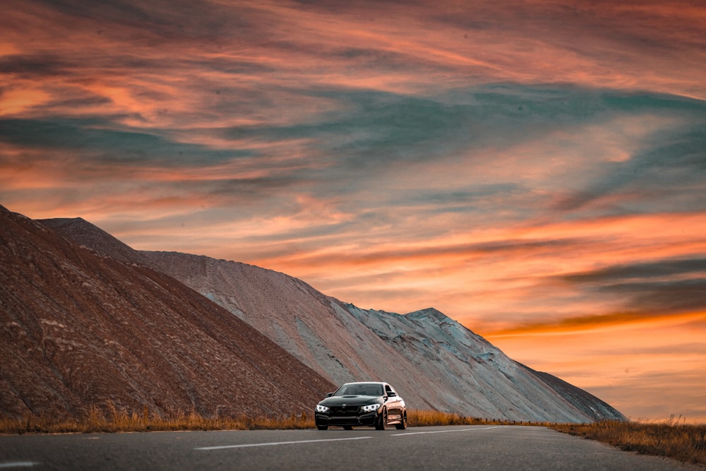 a car driving down a road with a mountain in the background