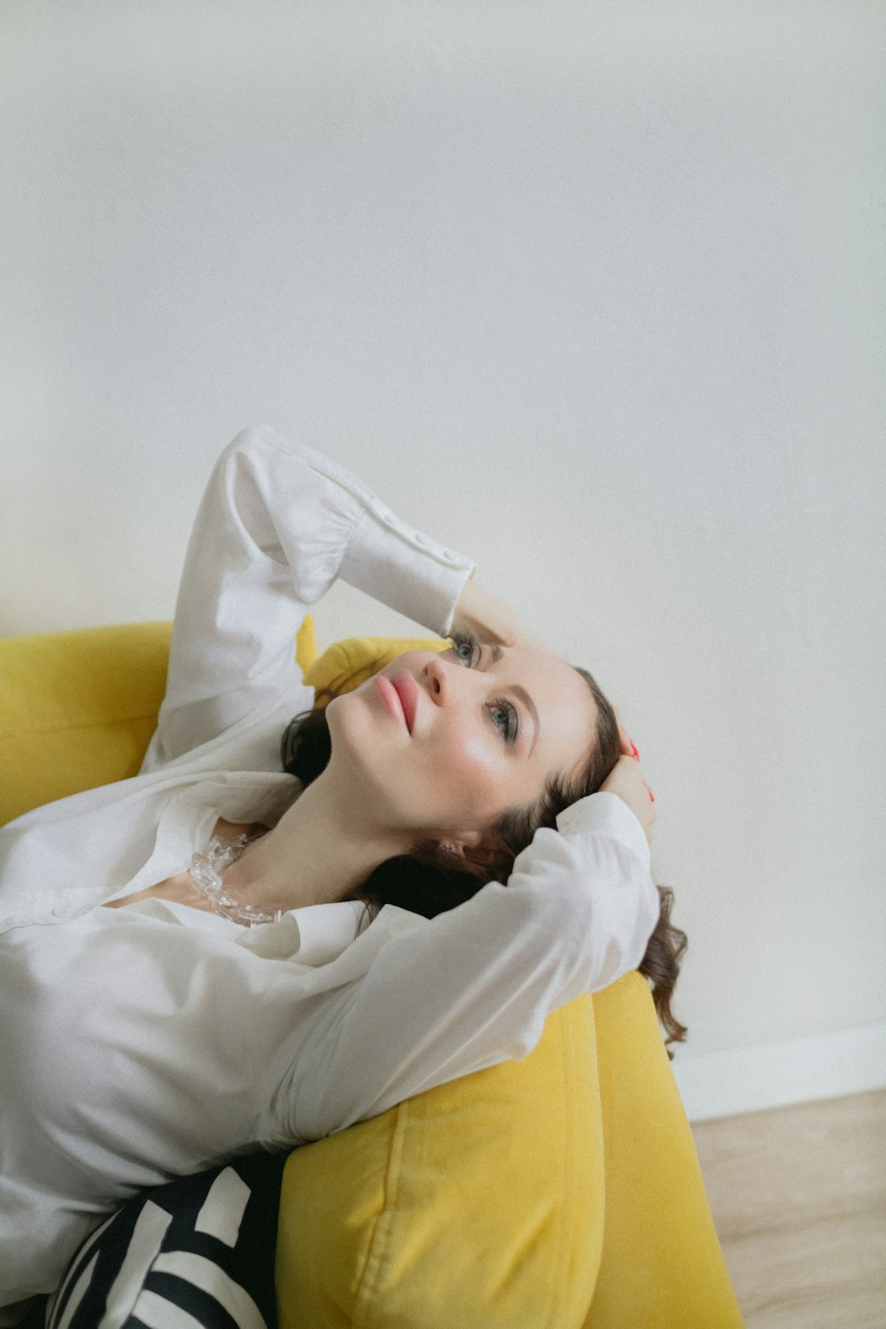 a woman laying on a yellow couch with her arms behind her head