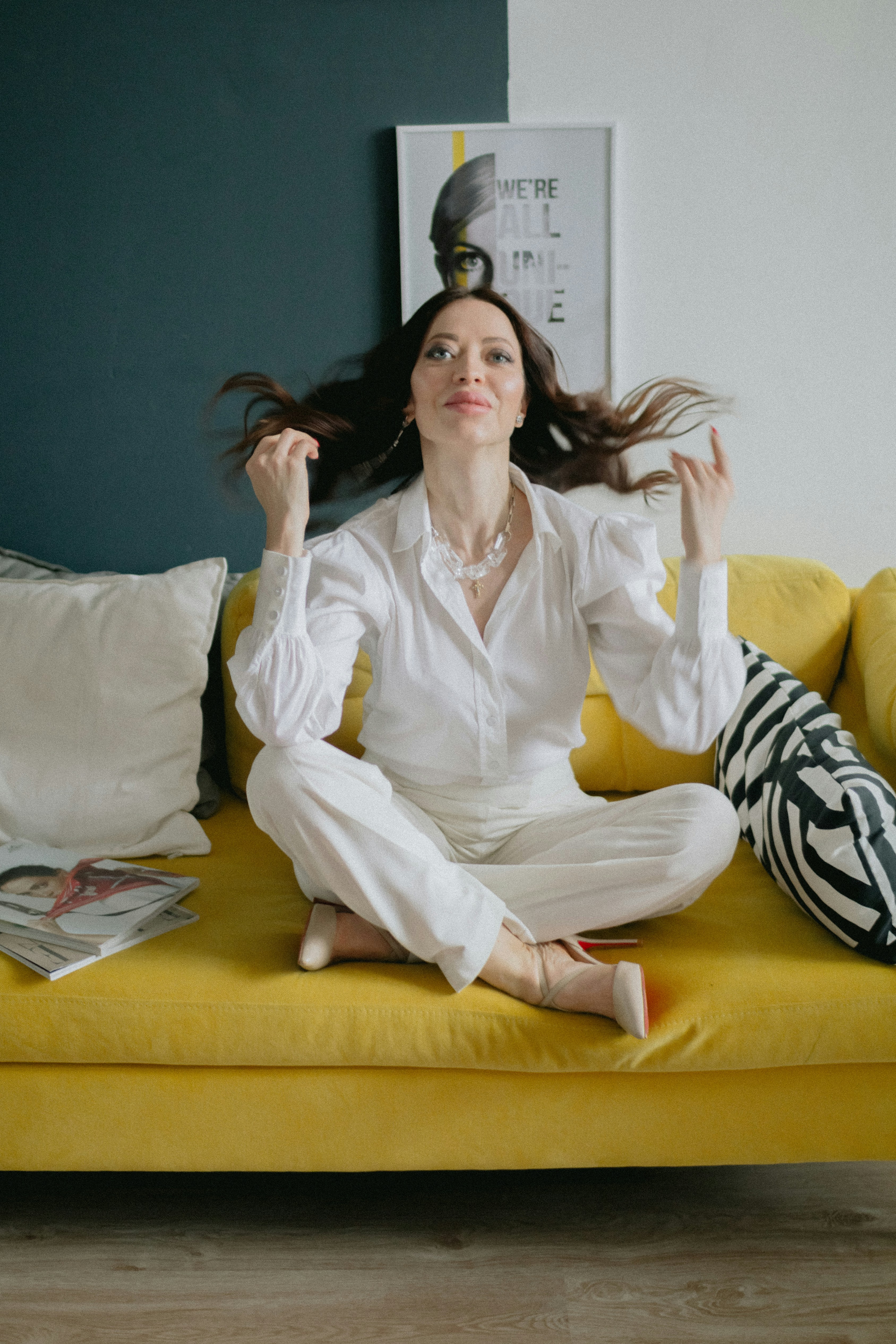 a woman sitting on a yellow couch with her hair blowing in the wind