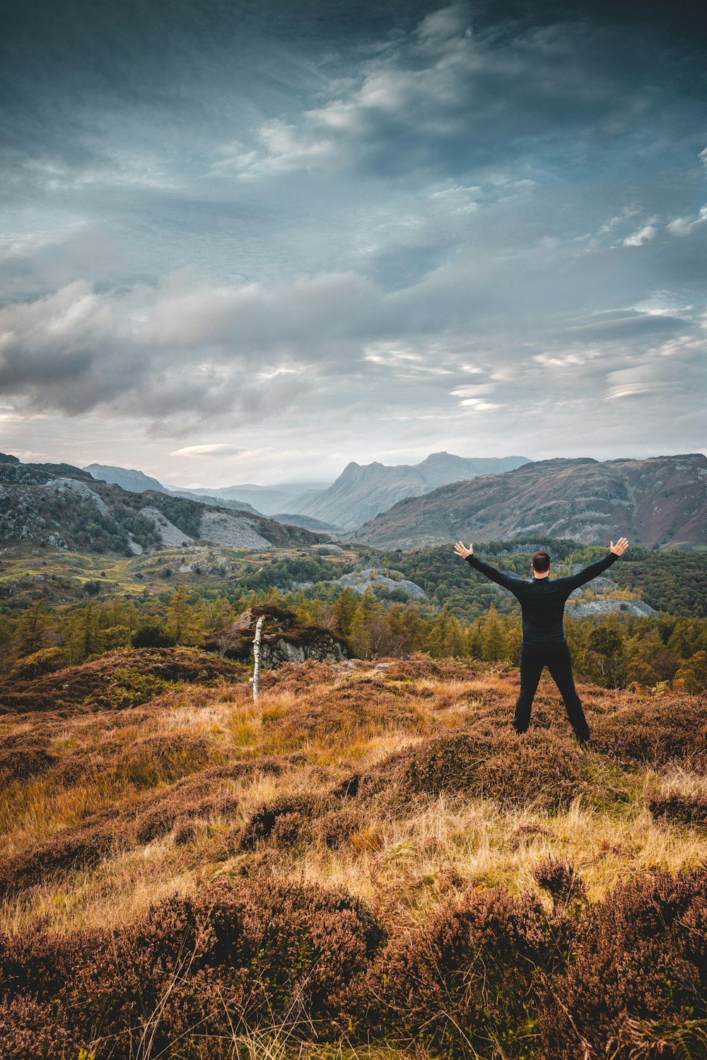 a man standing on top of a grass covered hillside