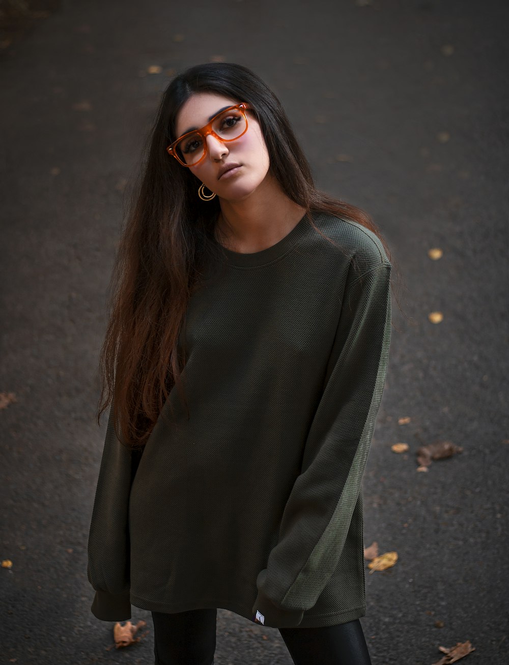 a woman with long hair wearing sunglasses and a green sweater