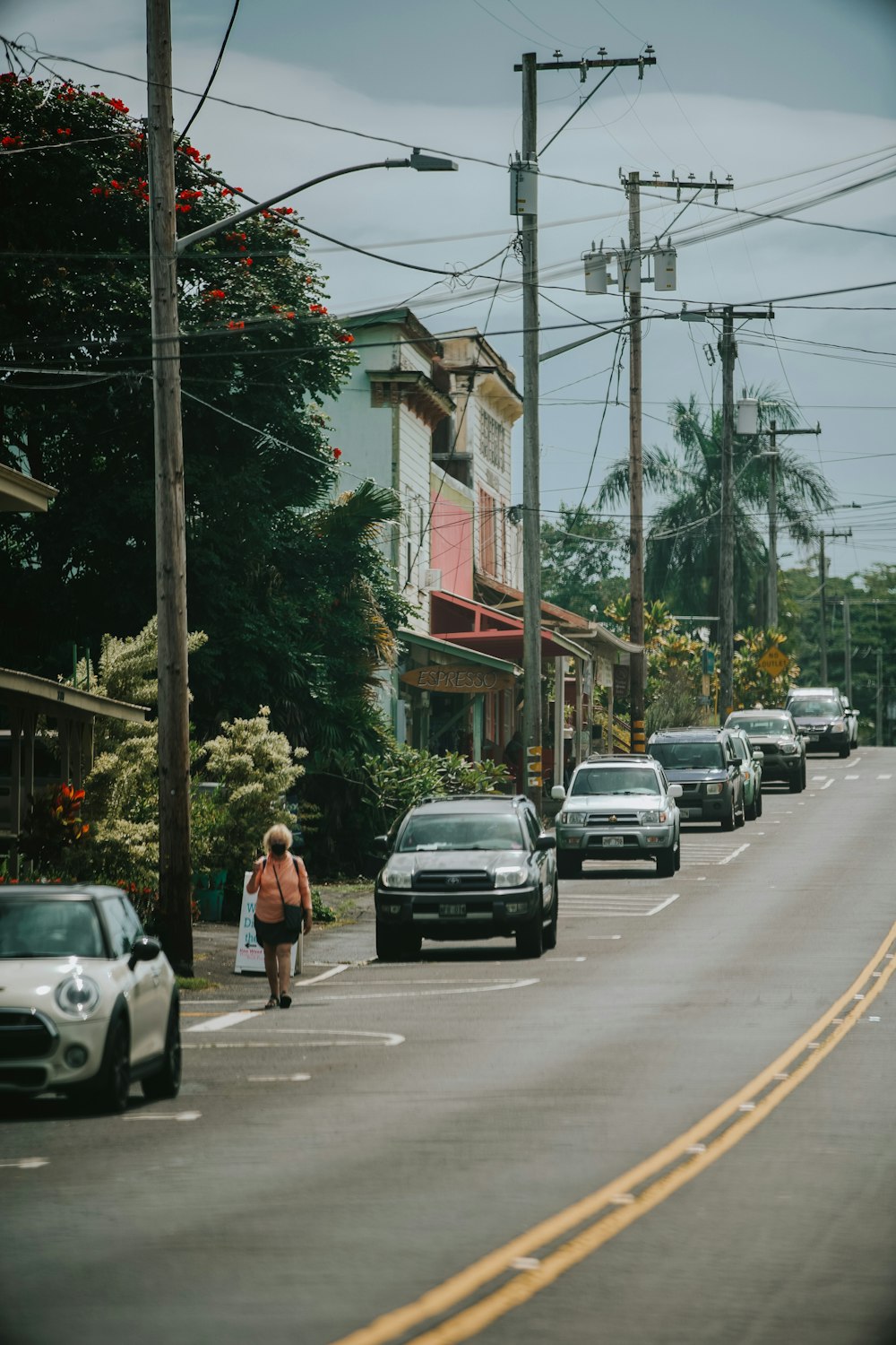 a woman walking down a street next to parked cars