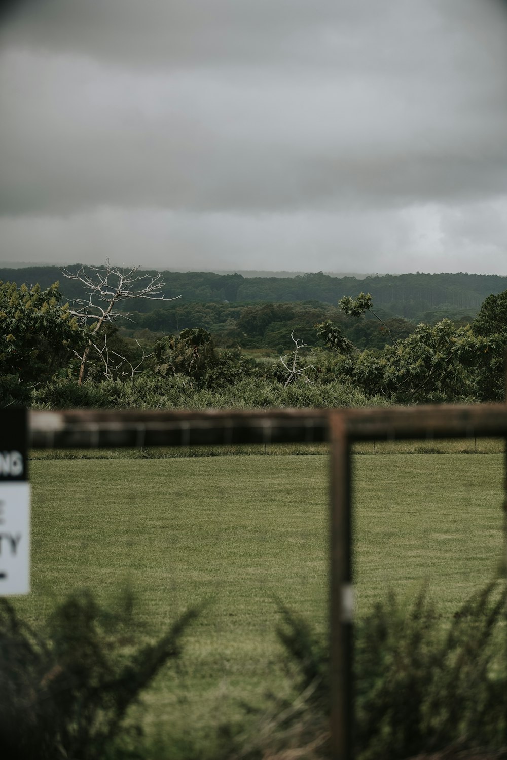 a field with a fence and a sign in the foreground