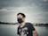 a man wearing a face mask by a body of water