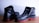 A pair of black leather shoes with a rugged design and distinct red soles placed against a light background. They appear sturdy and suitable for outdoor or work use.