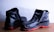 A pair of black leather shoes with a rugged design and distinct red soles placed against a light background. They appear sturdy and suitable for outdoor or work use.