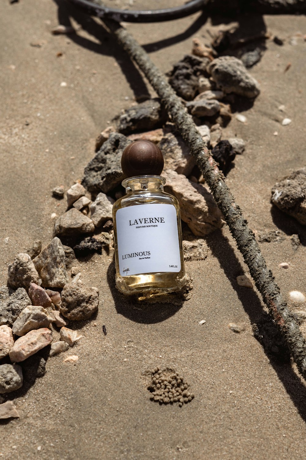 a bottle of perfume sitting on top of a sandy beach