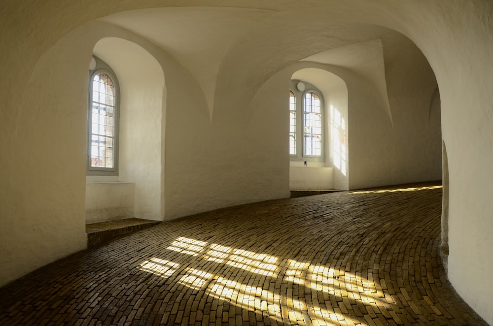 a room with a brick floor and arched windows