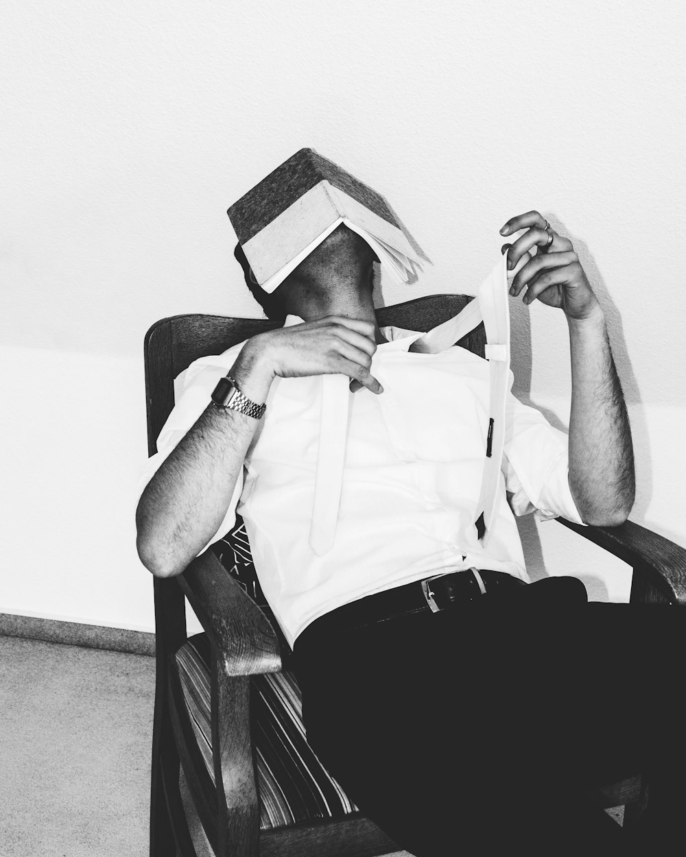 Ein Mann sitzt auf einem Stuhl mit einem Papierhut auf dem Kopf