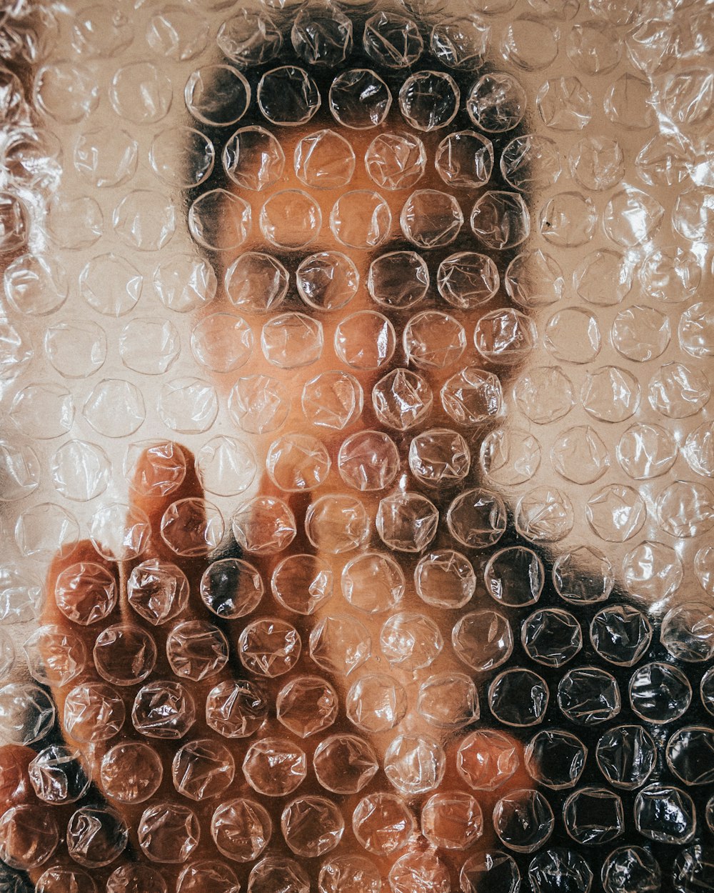 Un primer plano de la cara de una persona detrás de una envoltura de burbujas