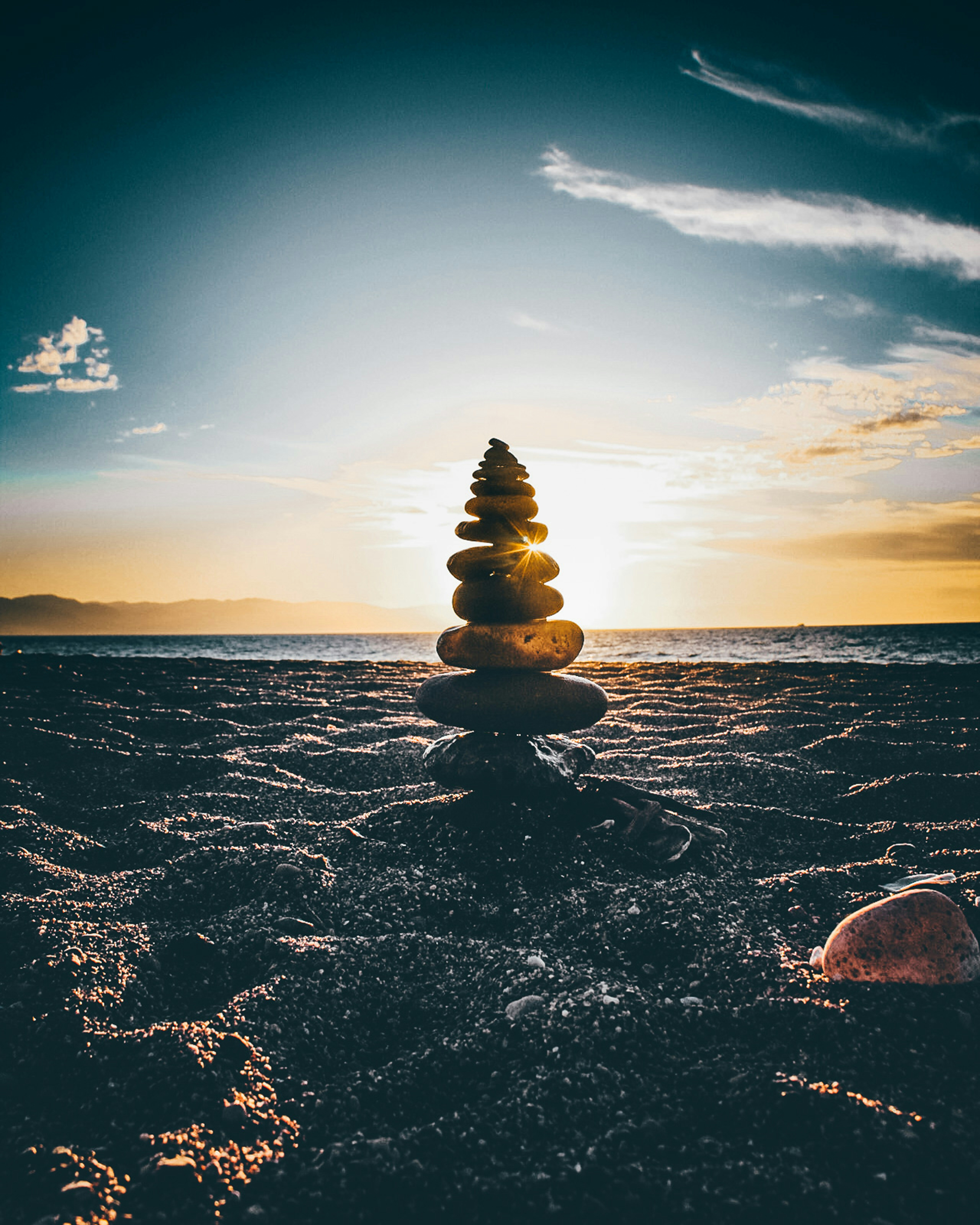 Tree made of a pile of rocks in front of the sunset