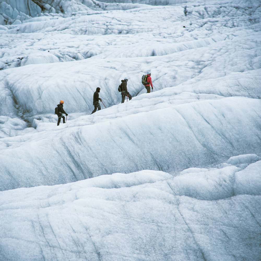 um grupo de pessoas caminhando através de uma encosta coberta de neve