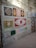A wall displays a variety of decorative tiles arranged in a grid-like pattern. Each tile features intricate designs, including floral motifs and geometric patterns, in colors like red, yellow, brown, and blue. The wall itself is made of exposed brick and concrete, giving a rustic appearance.