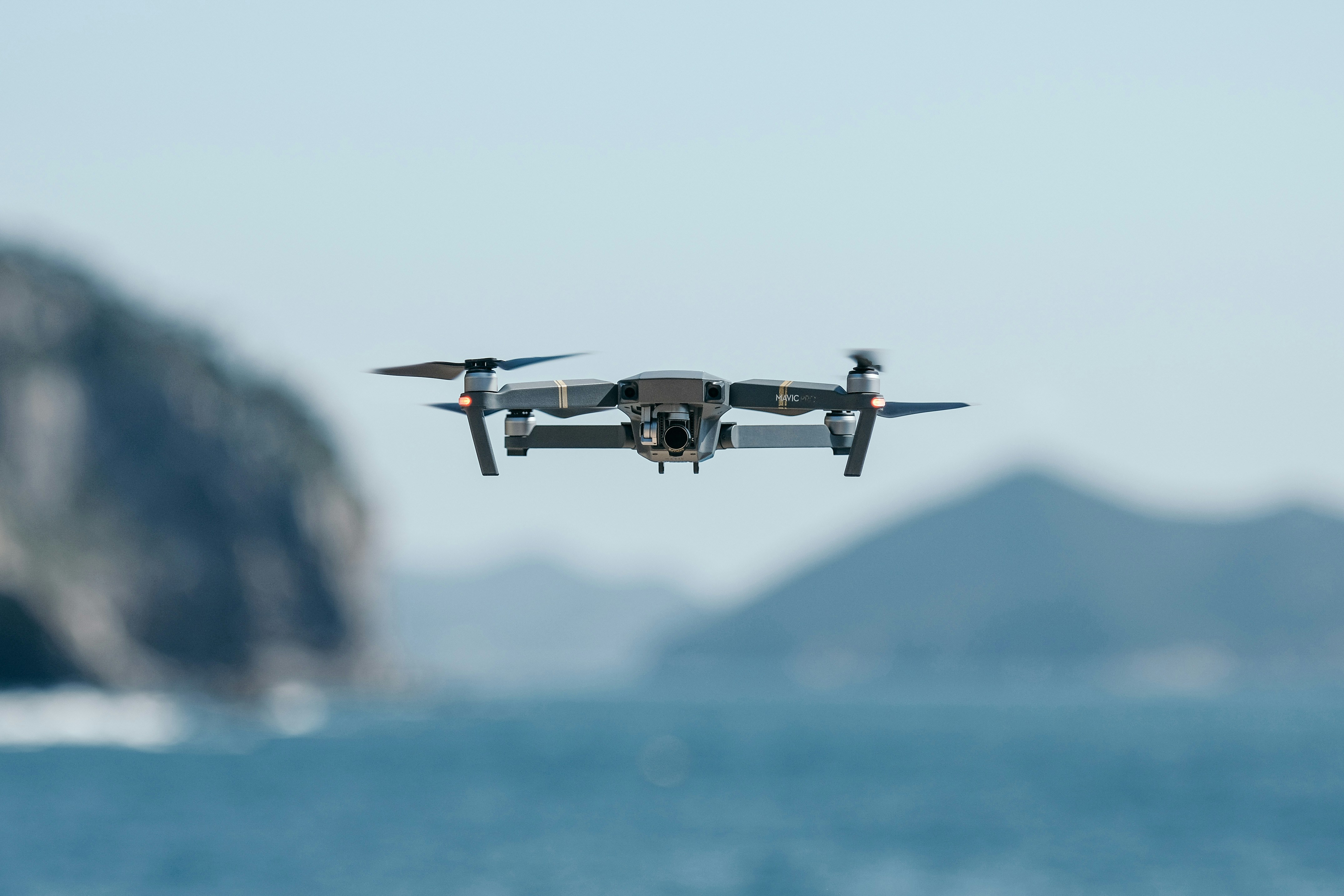 a small black and white plane flying over the ocean