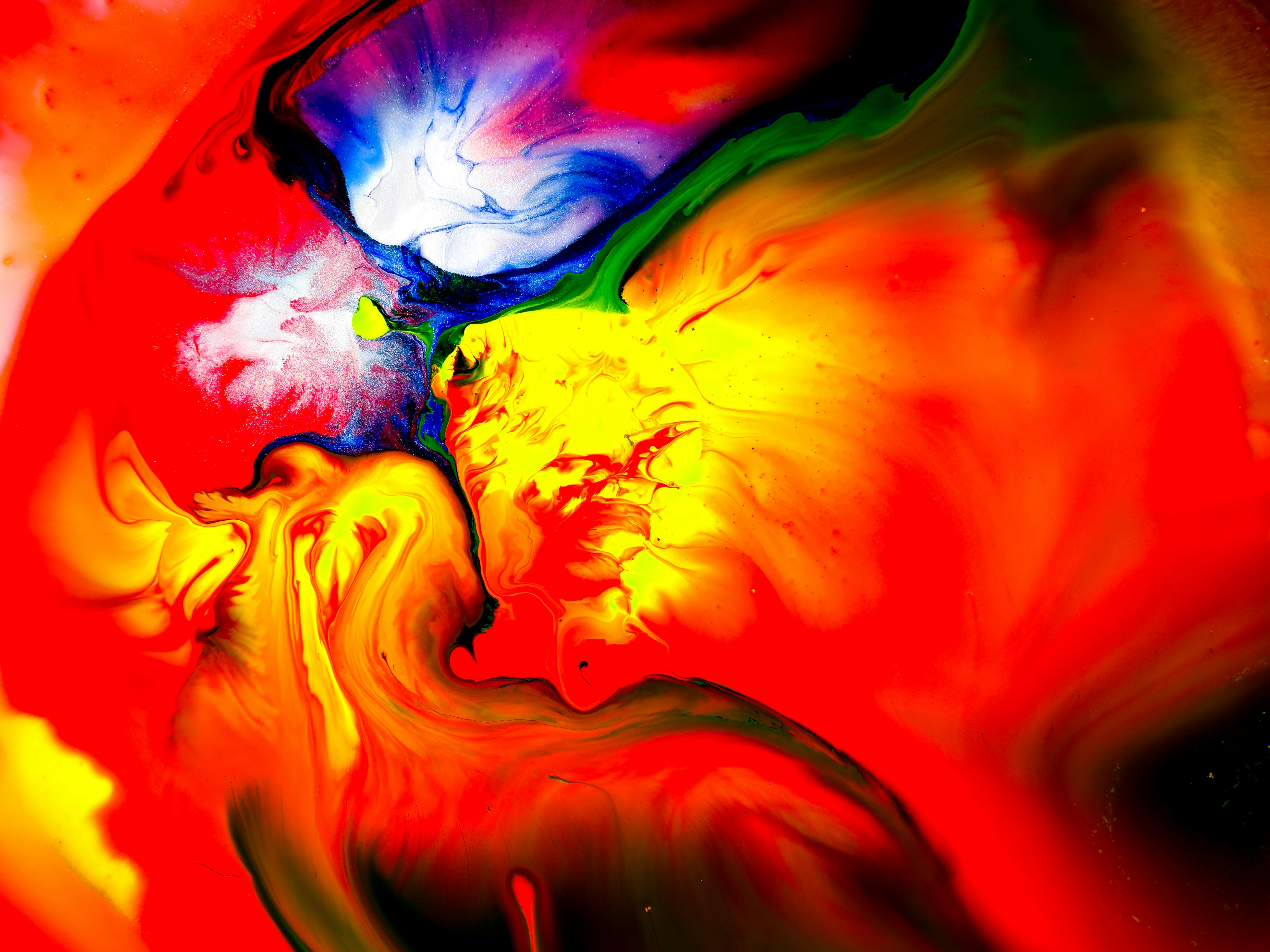 Red, yellow, blue, white, and green paints swirl together.