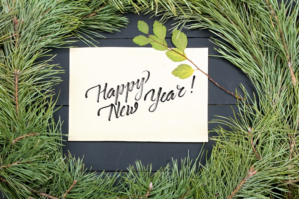 Una tarjeta de feliz año nuevo en la cima de un pino
