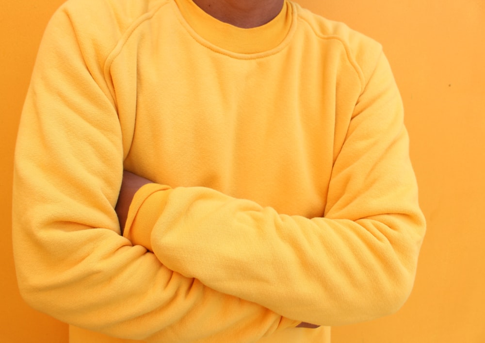 a man in a yellow sweatshirt with his arms crossed