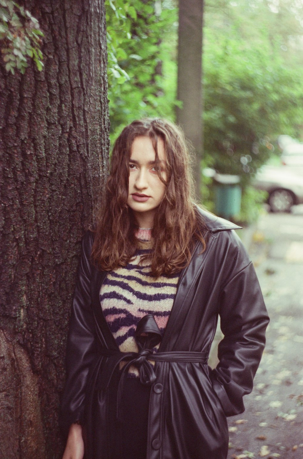 a woman standing next to a tree in a park