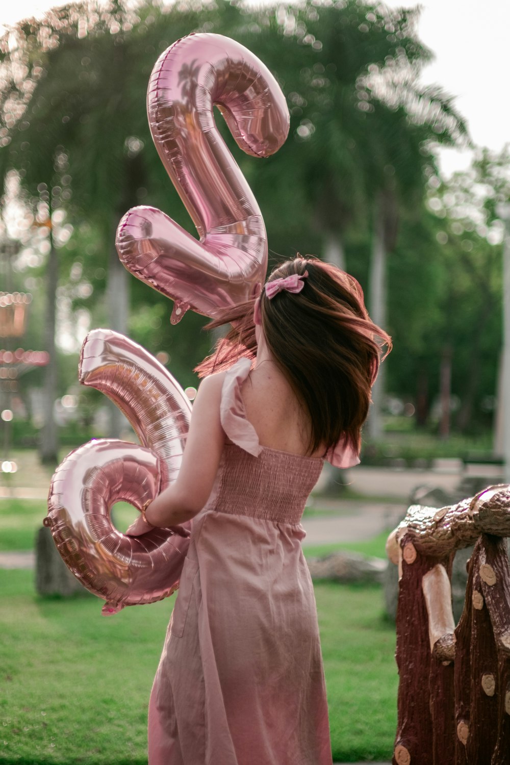 a girl in a pink dress holding a number six balloon